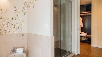 Een badkamer met een glazen douche, een wastafel en een handdoekrek.