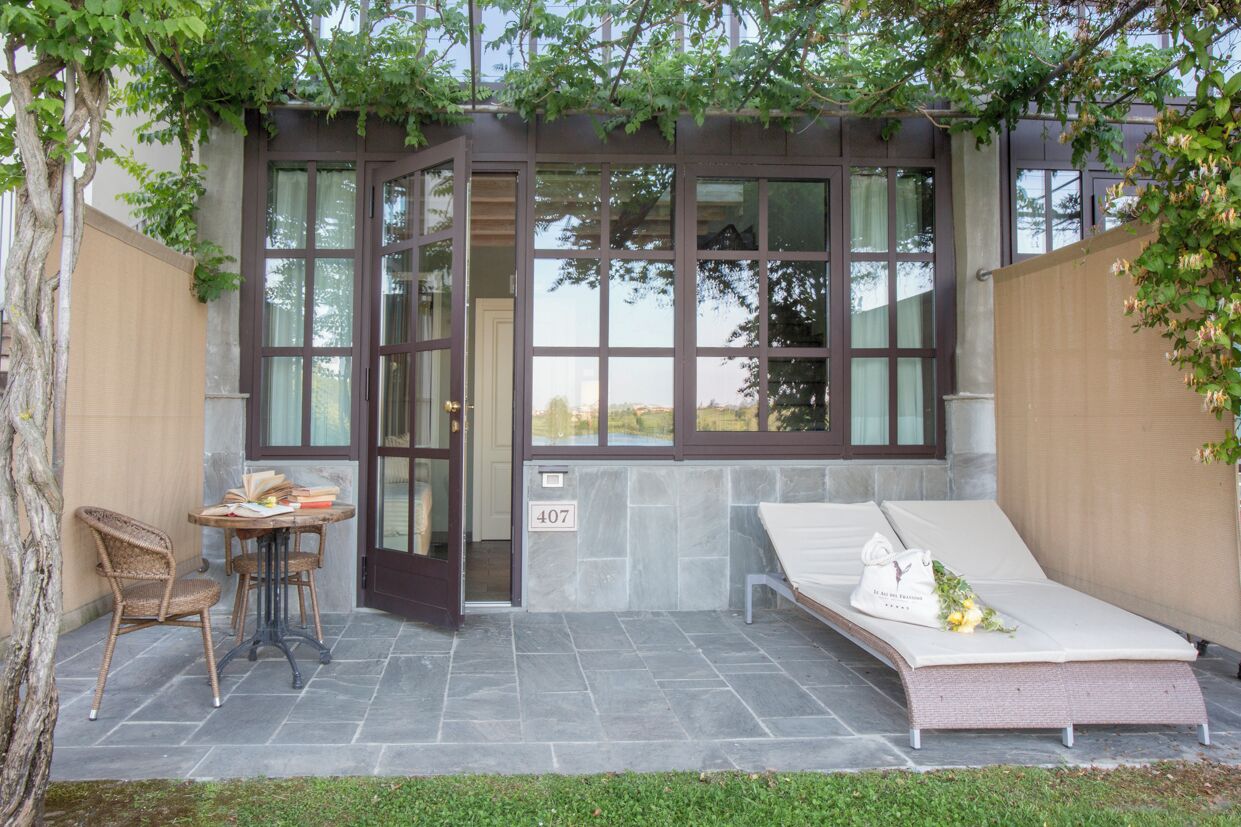 A small, private room with a glass door, a cushioned bench, and a table with books and a cup.
