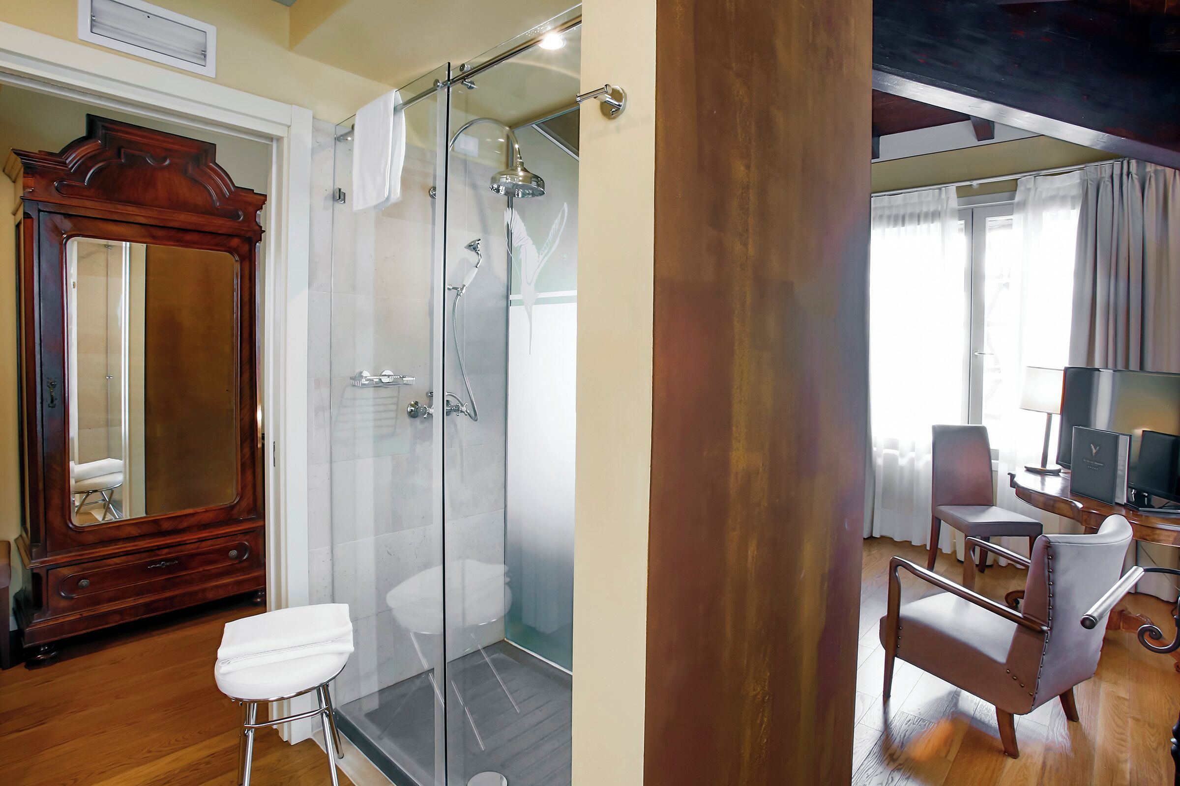 A bathroom with a glass-enclosed shower, a wooden vanity, and a white toilet.
