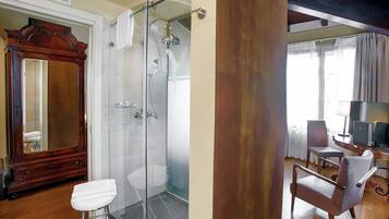 A bathroom with a glass-enclosed shower, a wooden vanity, and a white toilet.