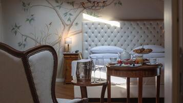 Ein Schlafzimmer mit einer gepolsterten Kopfteile, einem Esstisch mit Frühstücksangeboten, einem Stuhl und einem Nachttisch mit Lampe.