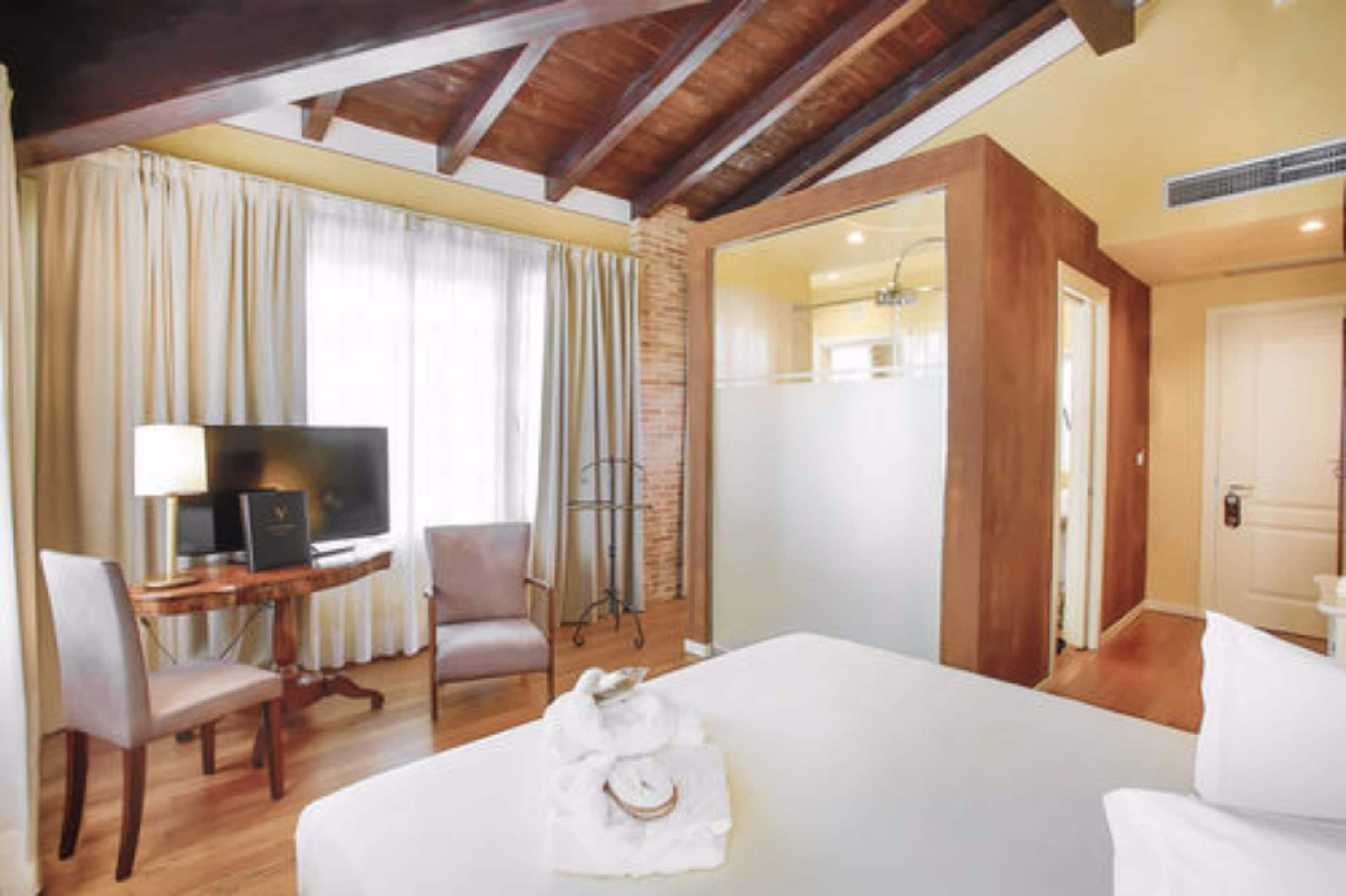 Une chambre d’hôtel avec un grand lit, un bureau avec un ordinateur, une chaise et un téléviseur.