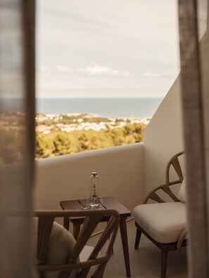 A balcony with a table, two chairs, a bottle, and glasses.