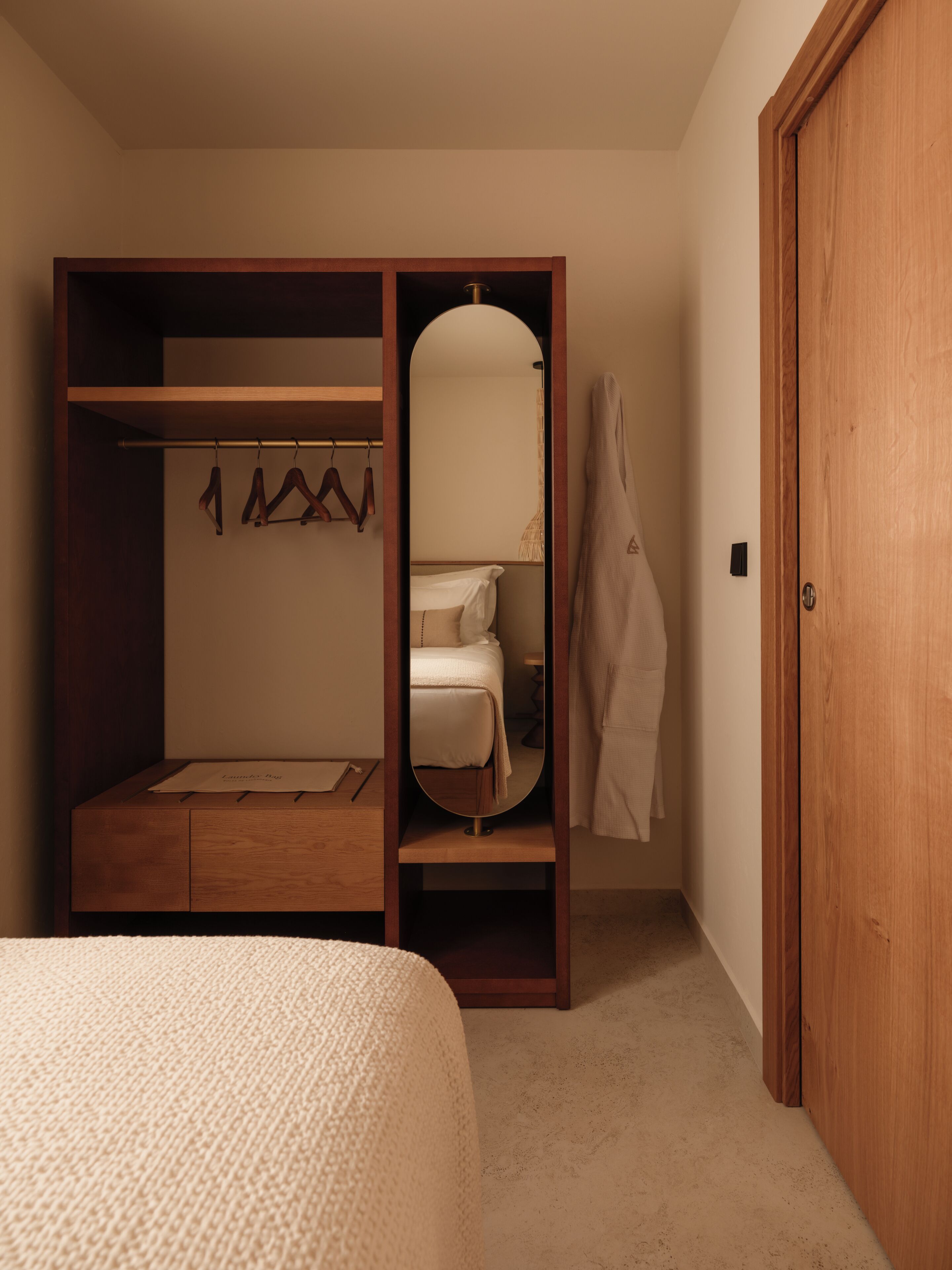 Un dormitorio con un armario de madera, una cama y un espejo.