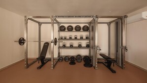 Une salle de sport équipée de matériel de musculation, notamment un support à squat, des bancs et divers poids.