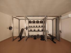A gym with weightlifting equipment, including a squat rack, benches, and various weights. - Besai Ibiza Boutique Hotel - New Opening (Sant Josep de sa Talaia)