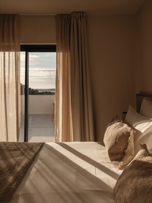 Habitación de hotel con cama, vista por una puerta de cristal y cortinas.