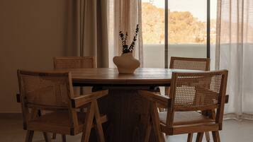 A dining area with a round wooden table, four wicker chairs, and a vase with flowers.