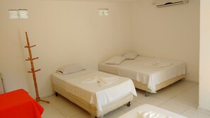 Une chambre avec deux lits, une chaise rouge et un porte-manteau en bois.