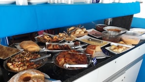 Buffet com diversos pratos, incluindo um bolo grande, pães variados e um prato com carne.