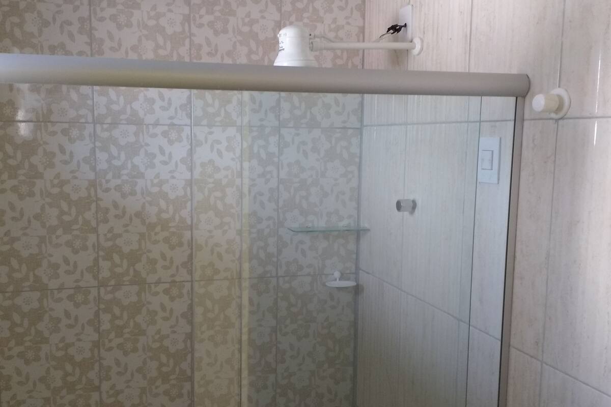A shower with a glass door, a white towel rack, and a wall-mounted towel dispenser.