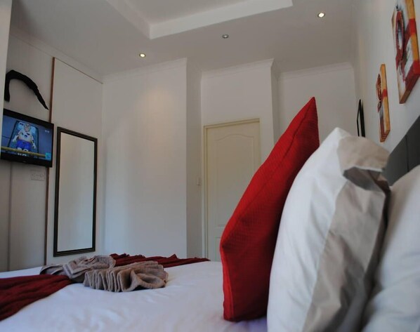 Una habitación de hotel con una cama, un televisor en la pared y una puerta.