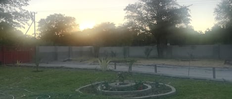 Un jardín con un parterre circular, un sendero empedrado y una cerca roja.