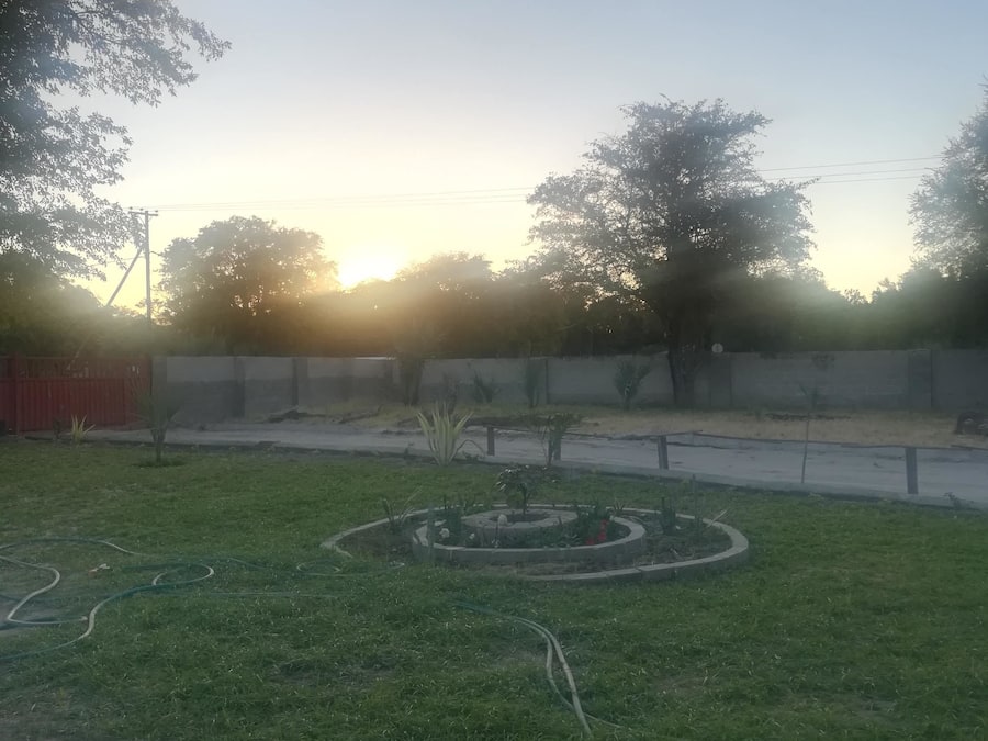 A garden area with a circular flower bed, a paved walkway, and a red fence.