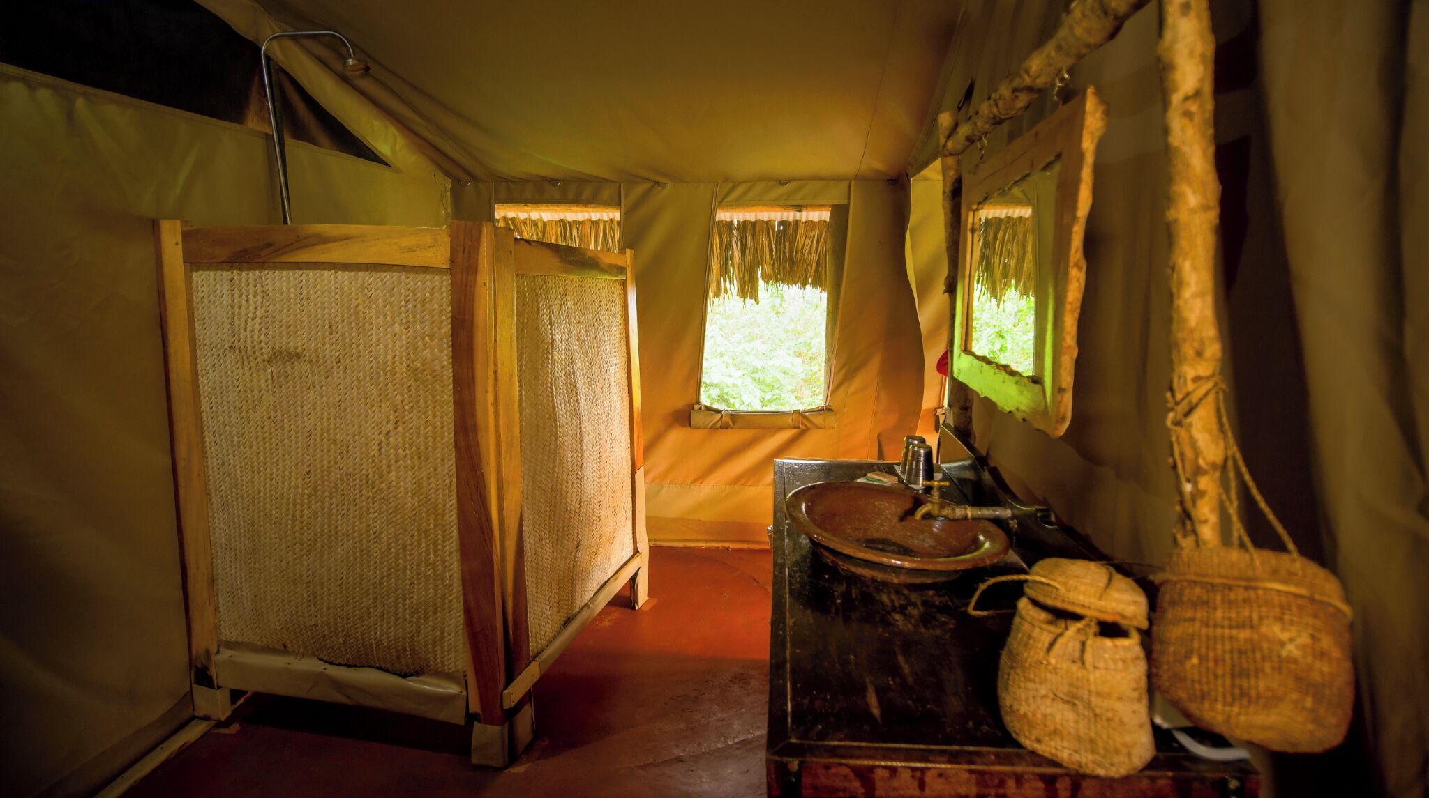 A tent with a wooden bed, a sink, and a window with curtains.