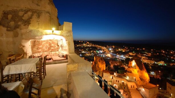 A stone interior with a view of a city at night. - Arif Cave Hotel (Nevsehir)
