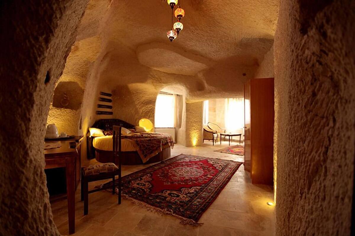A cozy, cave-like bedroom with a bed, a desk, a chair, and a large rug.