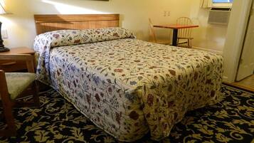A room with a bed, a chair, a table, and a painting on the wall.
