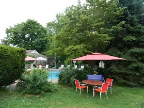 Patio con piscina, sombrillas rojas y mobiliario exterior.