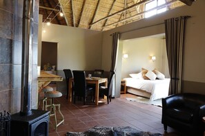 A room with a fireplace, a dining area, a bed, and a bathroom. - Imla Guest Farm (Setsoto)