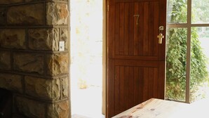 A wooden door with a number 7, a stone wall, and a view of greenery outside. - Imla Guest Farm (Setsoto)