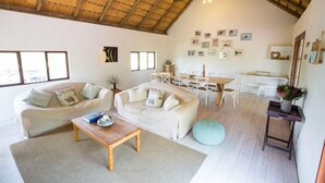 A spacious living area with two sofas, a coffee table, and a dining table with chairs. - Ngama Tented Safari Lodge (Hoedspruit)