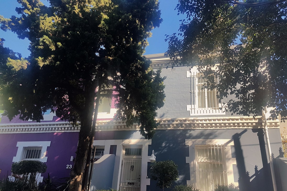 A row of two-story houses with a traditional architectural style, featuring a central entrance and a small front garden.