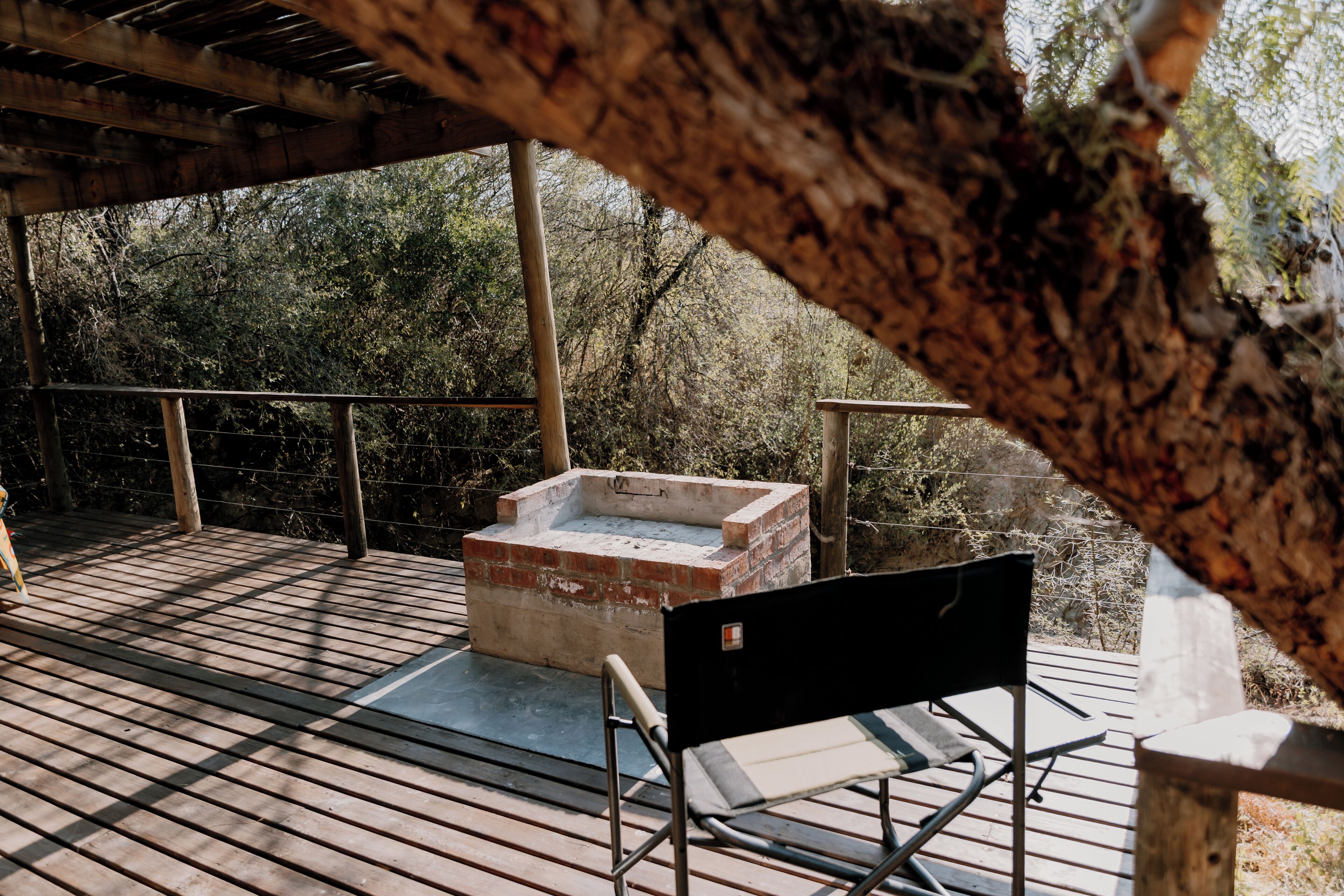 A wooden deck with a brick structure, a metal chair, and a railing.