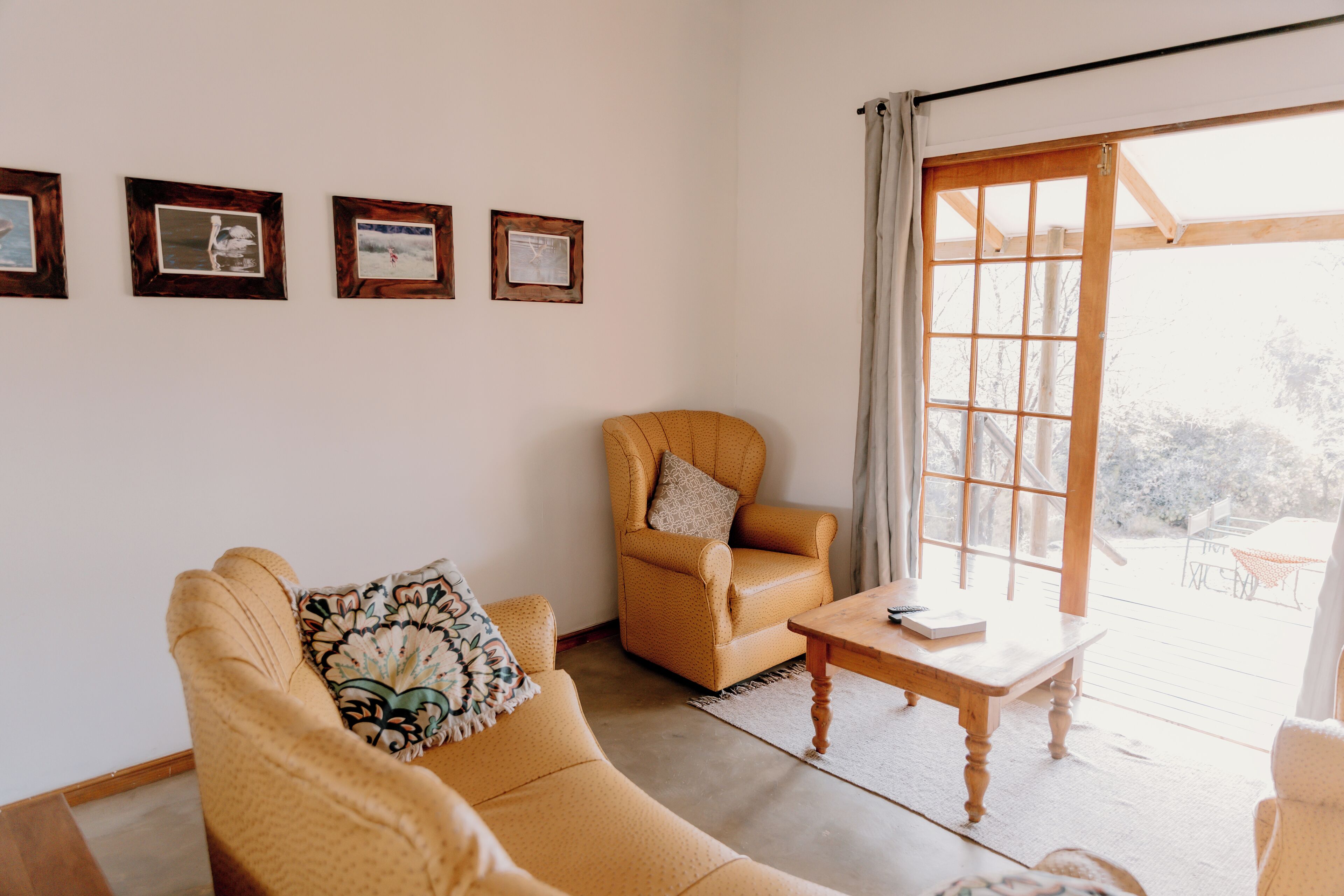 Una sala de estar con un sofá, un sillón y una mesa. Cuatro cuadros enmarcados adornan la pared.