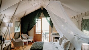 Un hébergement sous tente comprenant un lit, une chaise, un bureau et une lampe.