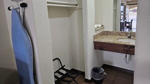 Un baño con lavamanos, espejo, toallero y cubo de basura.