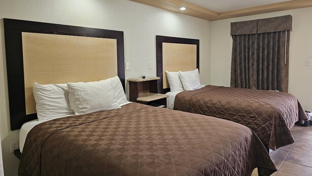 Una habitación de hotel con dos camas, cada una con cabecera y mesita de noche.
