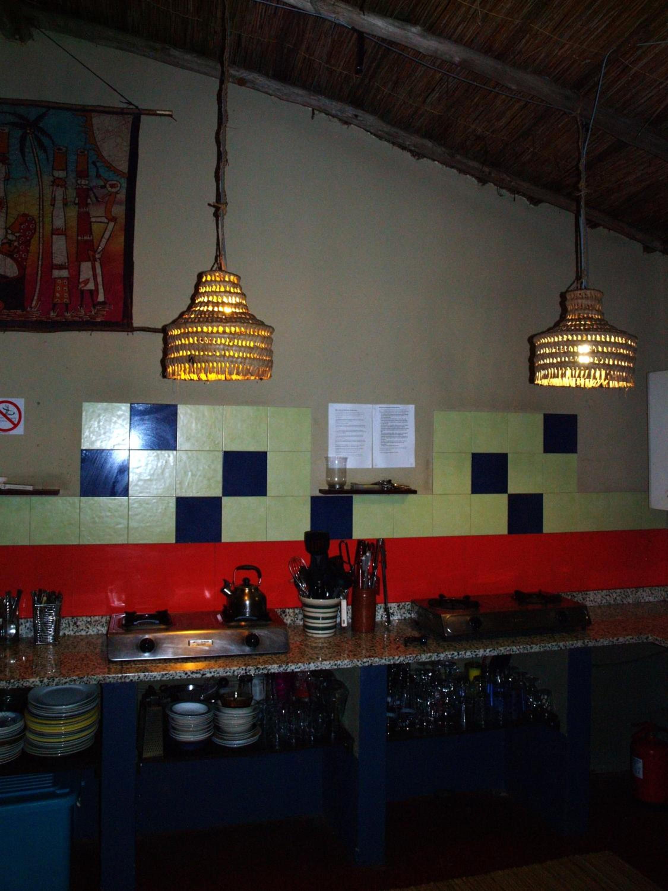 Una cocina con salpicadero rojo, luces colgantes y una pared con azulejos que muestra un menú.