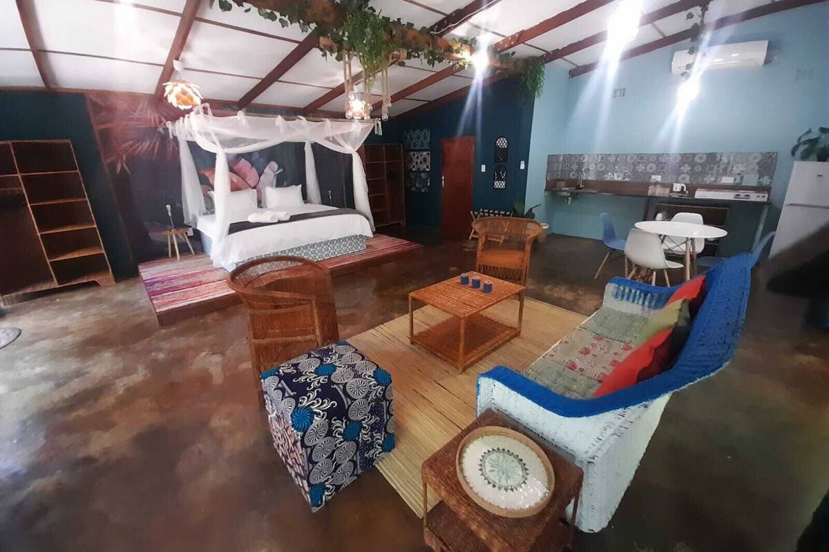 A cozy room with a bed, a dining table, a chair, and a small table with decorative items.