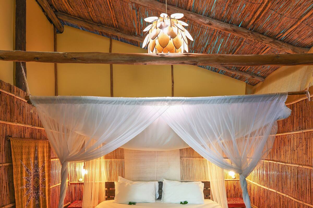 A bed with a canopy, wooden walls, and a patterned floor.