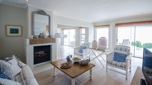 A spacious living room with a fireplace, comfortable seating, and large windows offering a view.