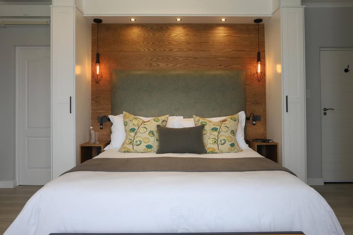 A modern hotel room with a large bed, wooden headboard, and two bedside tables with lamps.