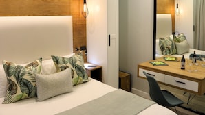 Une chambre d’hôtel moderne avec un grand lit, un mur décoratif en bois, un bureau avec un miroir et une chaise.