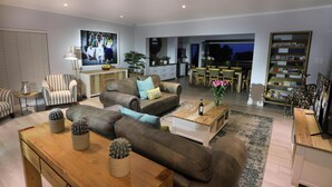 Un salon moderne avec un ensemble de canapés, une table basse sur laquelle se trouve une bouteille, et un cactus servant de décoration centrale.
