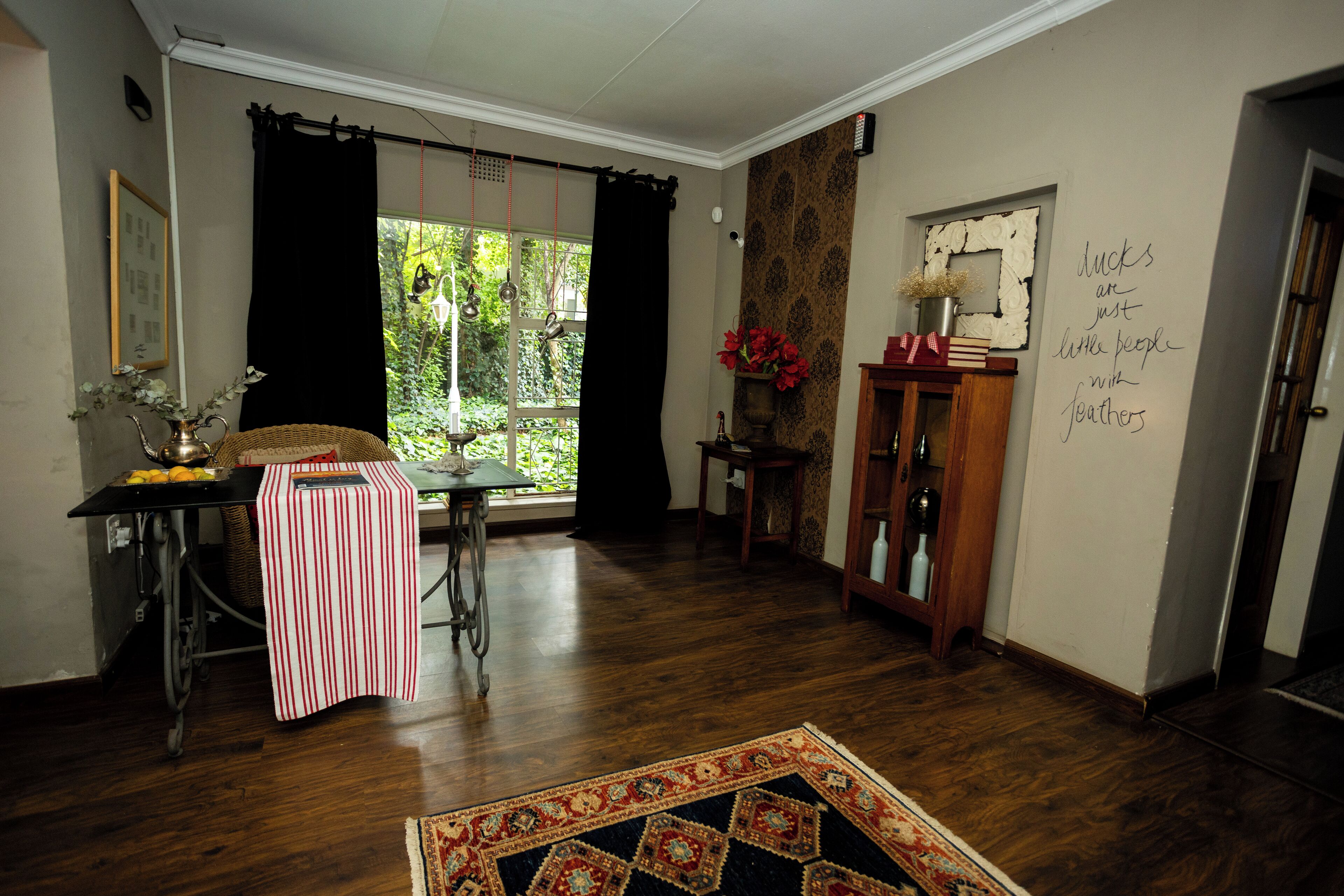 A room with a dining table, chairs, a window with curtains, a cabinet, and a wall with a decorative item.