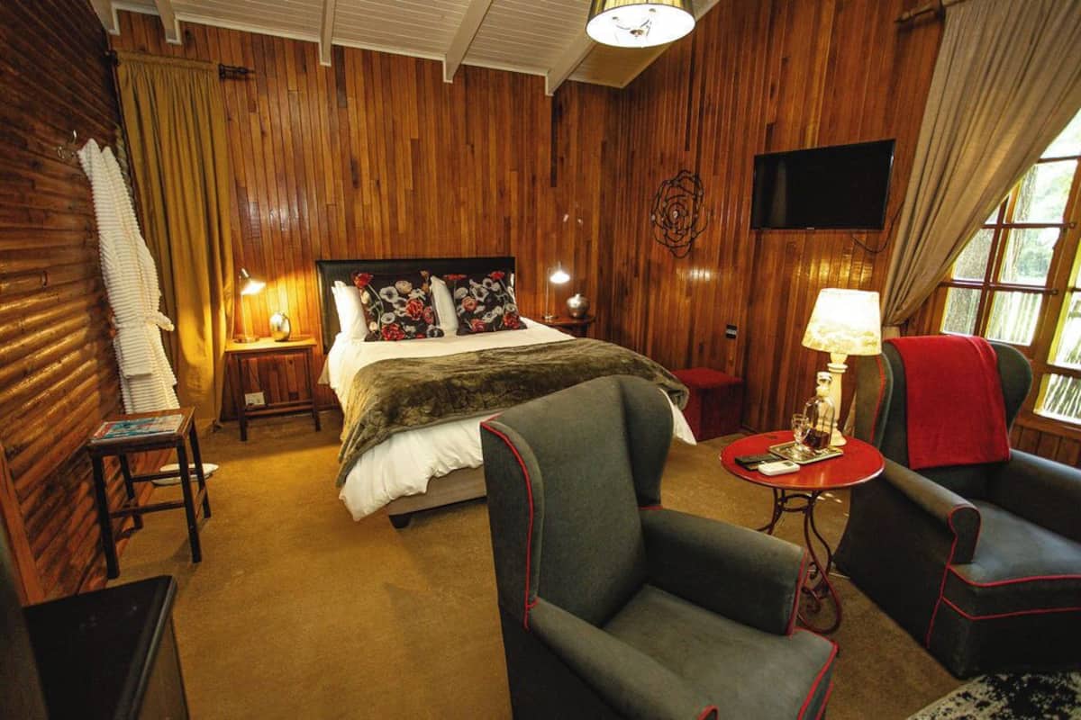 Una habitación con paneles de madera, una cama, una silla, una mesa y un televisor.
