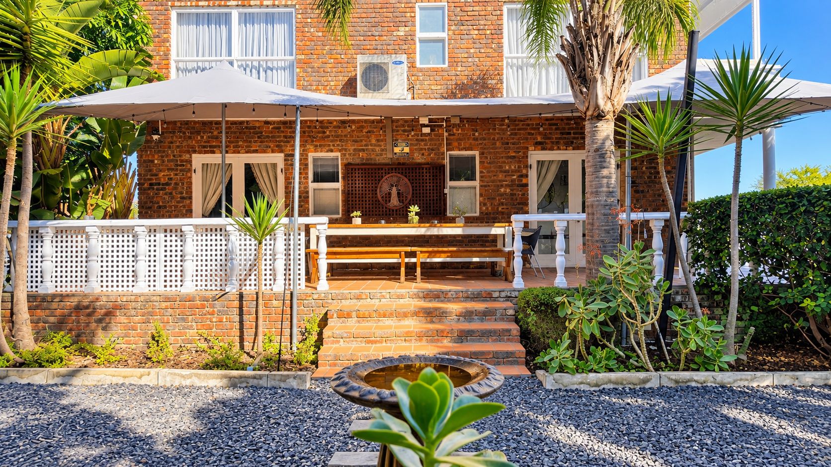 A brick building with a patio area, outdoor seating, and a small water feature.