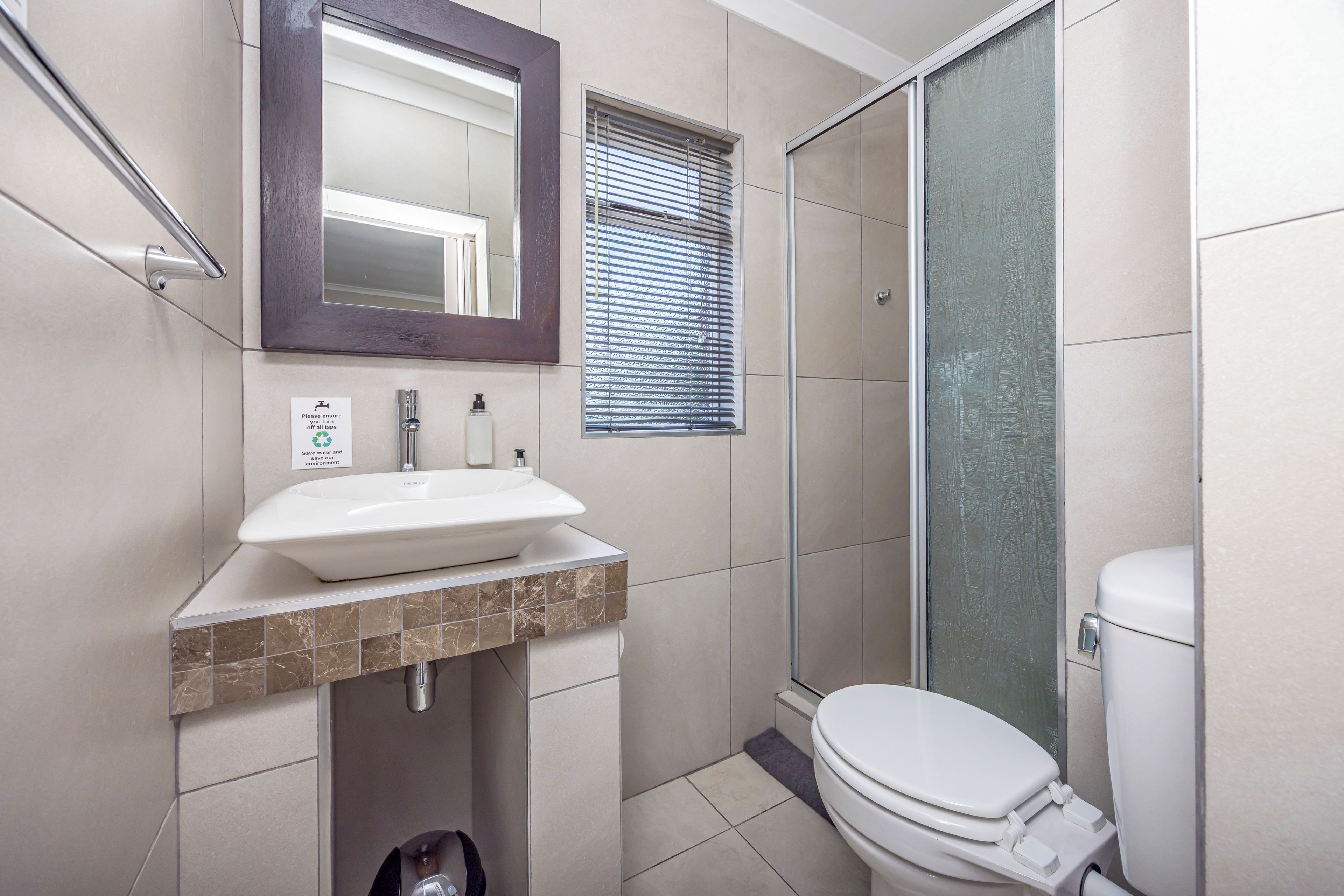 A bathroom with a sink, mirror, toilet, and shower.