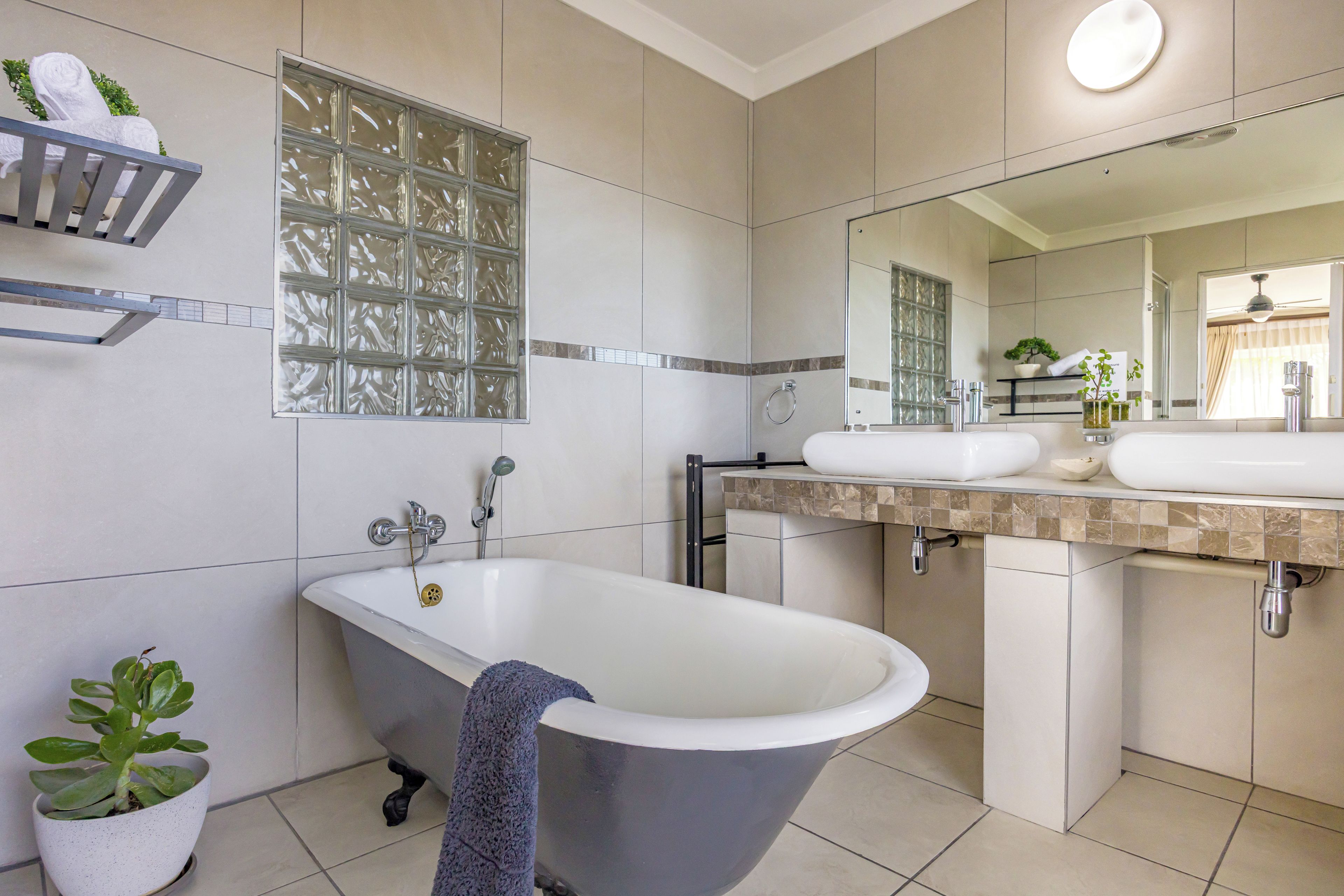 Une salle de bain moderne avec une baignoire sur pieds, un grand miroir et un meuble-lavabo doté de deux vasques.