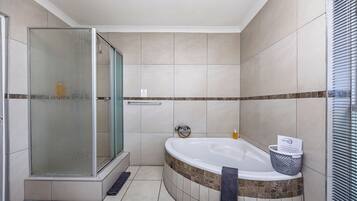 A modern bathroom with a glass-enclosed shower, a freestanding bathtub, and a tiled floor.