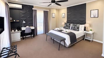 A hotel room with a bed, desk, chair, and a ceiling fan.