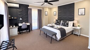 Une chambre d’hôtel équipée d’un lit, d’un bureau, d’une chaise et d’un ventilateur de plafond.