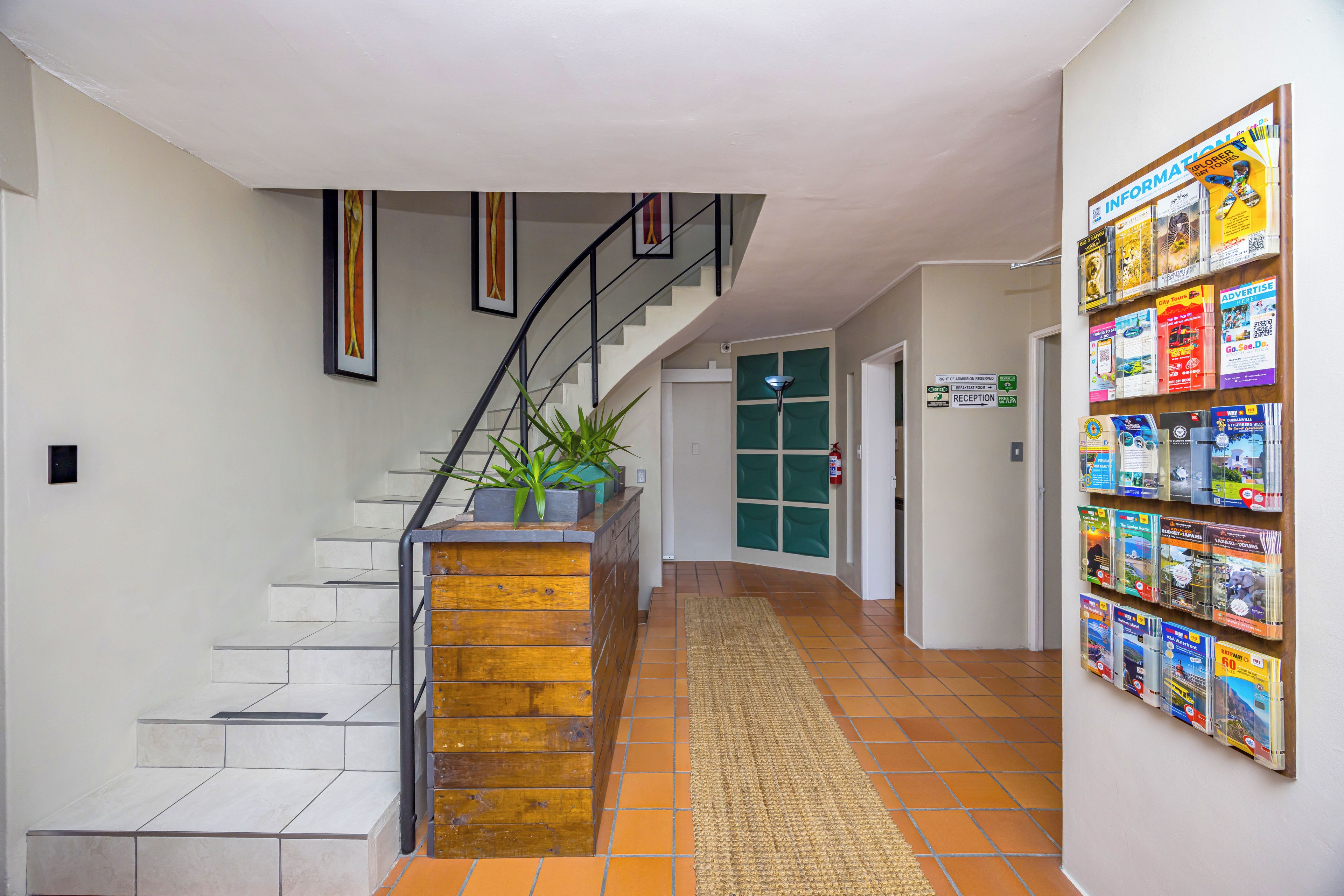 Un pasillo con una escalera, un letrero de recepción y una pared con folletos.