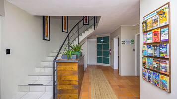 Un pasillo con una escalera, un letrero de recepción y una pared con folletos.