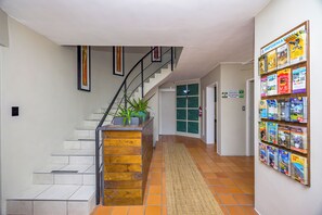 A hallway with a staircase, a reception sign, and a wall with brochures.